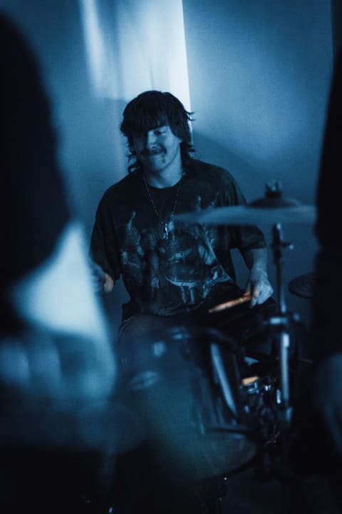 Calvin drumming at Blind Temptress’s first show under blue stage light